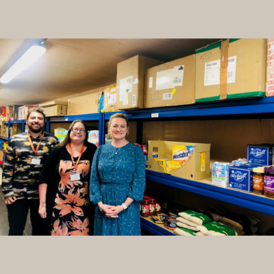 Community supermarket pilot. 2 staff members of CVS and another person in a storeroom with boxes of food/household essentials.